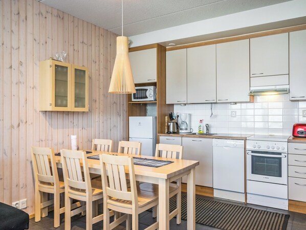 A compact kitchen with white cabinets, a microwave, a coffee maker, and a Bosch oven. - Rukatonttu d21 by Interhome (Kuusamo)