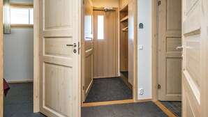 Un couloir avec des portes en bois, un hall d’entrée recouvert d’un tapis et une petite fenêtre.