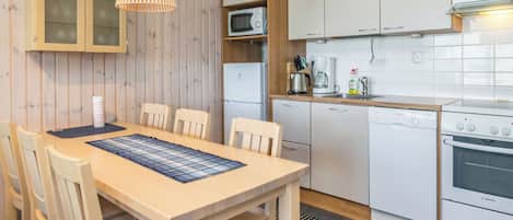 A compact kitchen with white cabinets, a microwave, a Bosch dishwasher, and a stove.