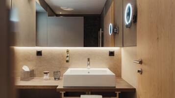 A modern bathroom with a large mirror, a rectangular sink, and a wooden vanity.