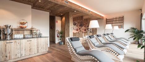 A spa area with wooden floors, a reception desk, and multiple sun loungers with cushions.