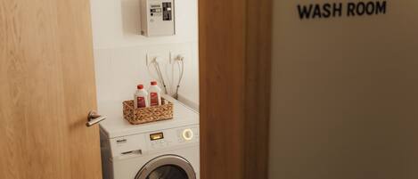 Una lavadora con panel de control y una cesta de botellas de detergente.