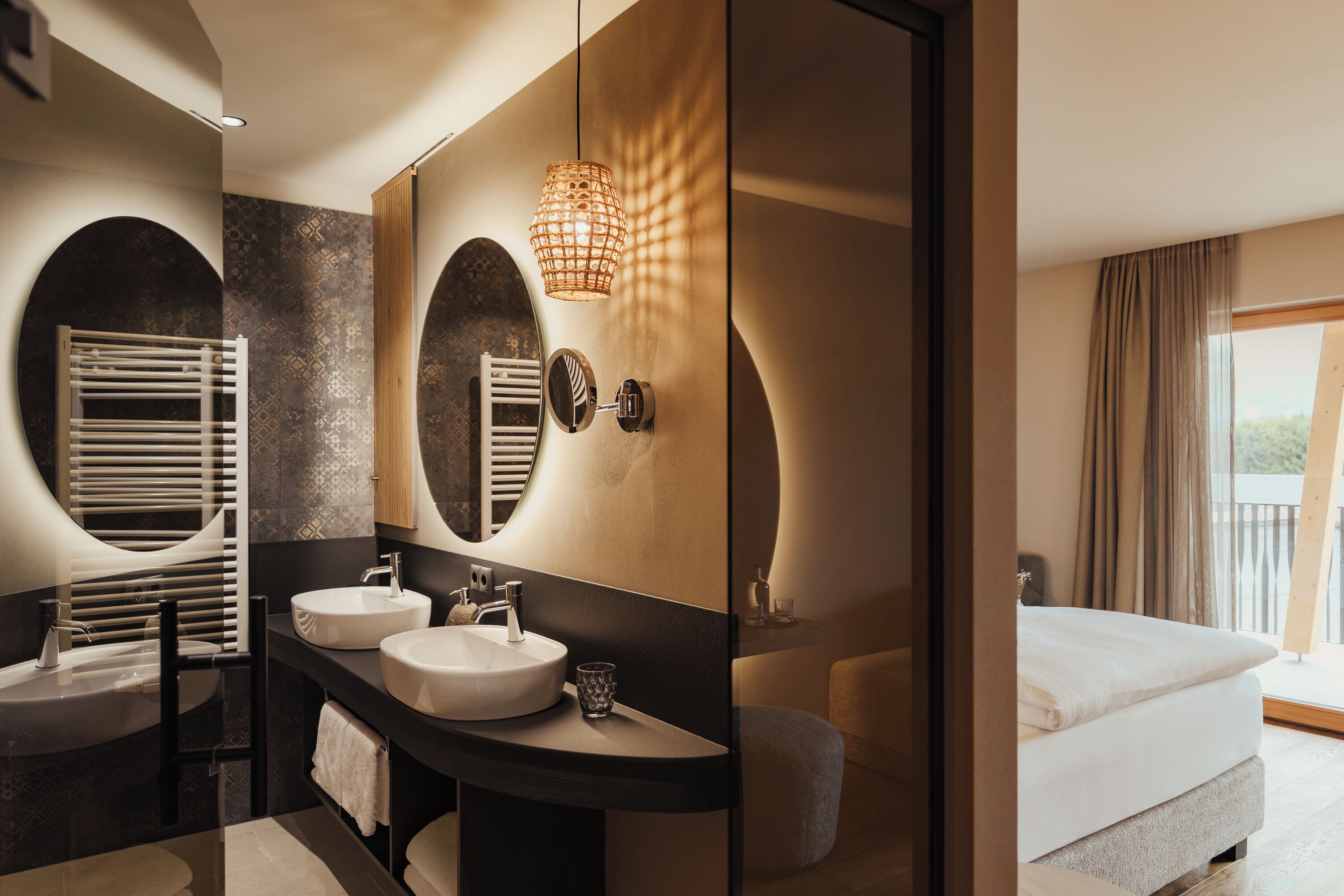 A modern bathroom with two sinks, a large mirror, and a unique circular design on the wall.
