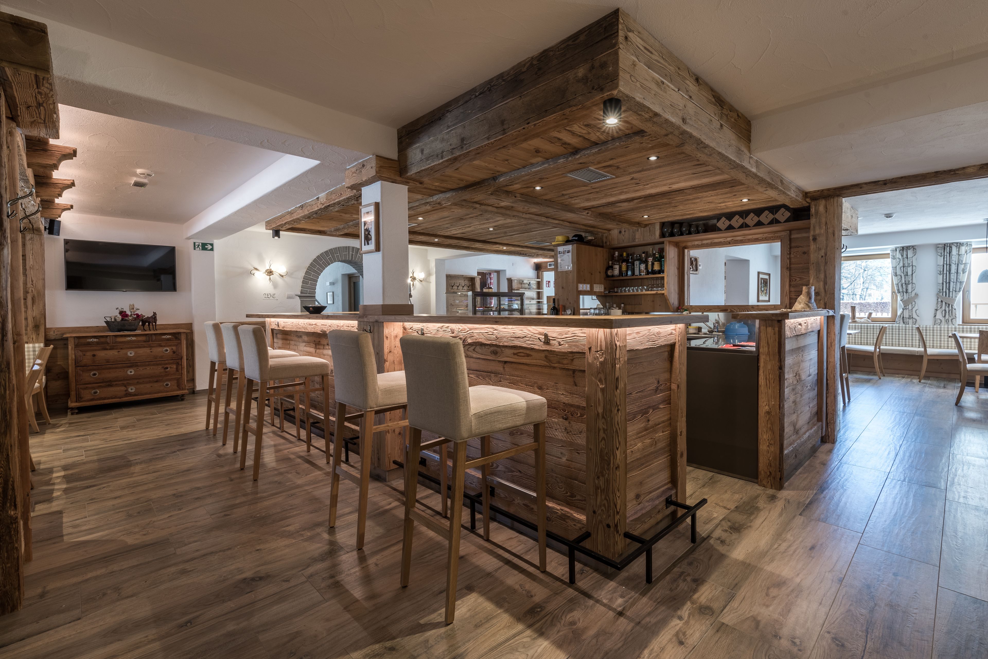 A rustic interior with a wooden bar area, bar stools, and a dining area with chairs.