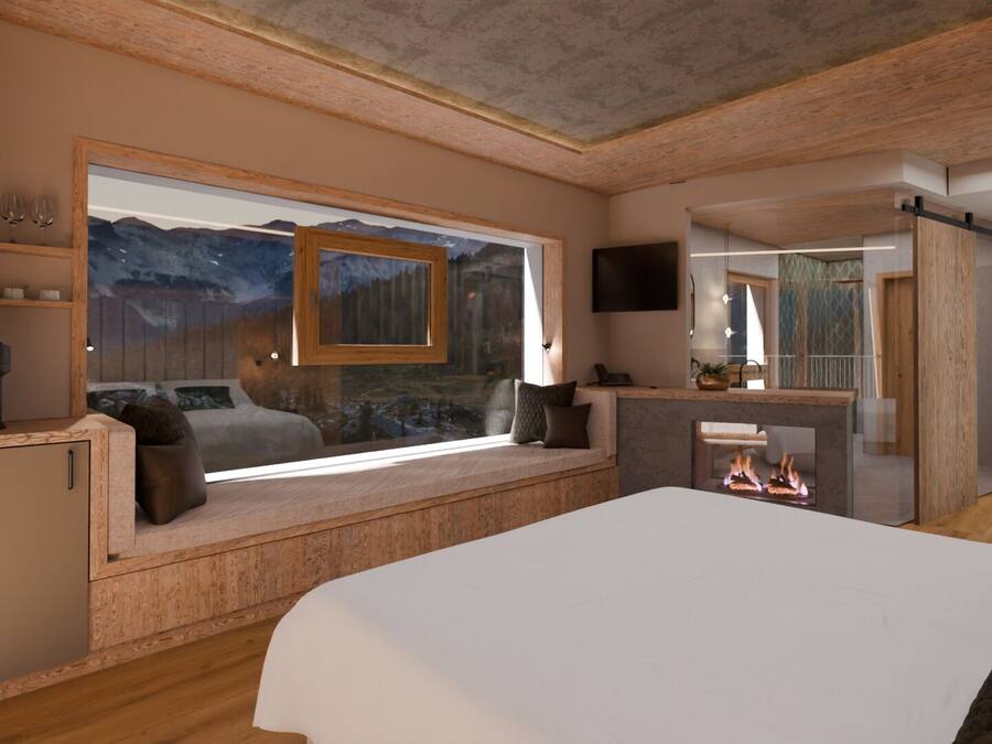 Un dormitorio con un ventanal grande, chimenea, cama y una kitchenette pequeña.
