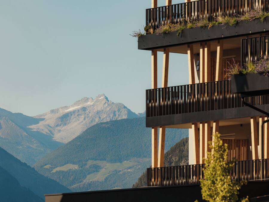 Un edificio de varios pisos con balcones, cada uno decorado con plantas.