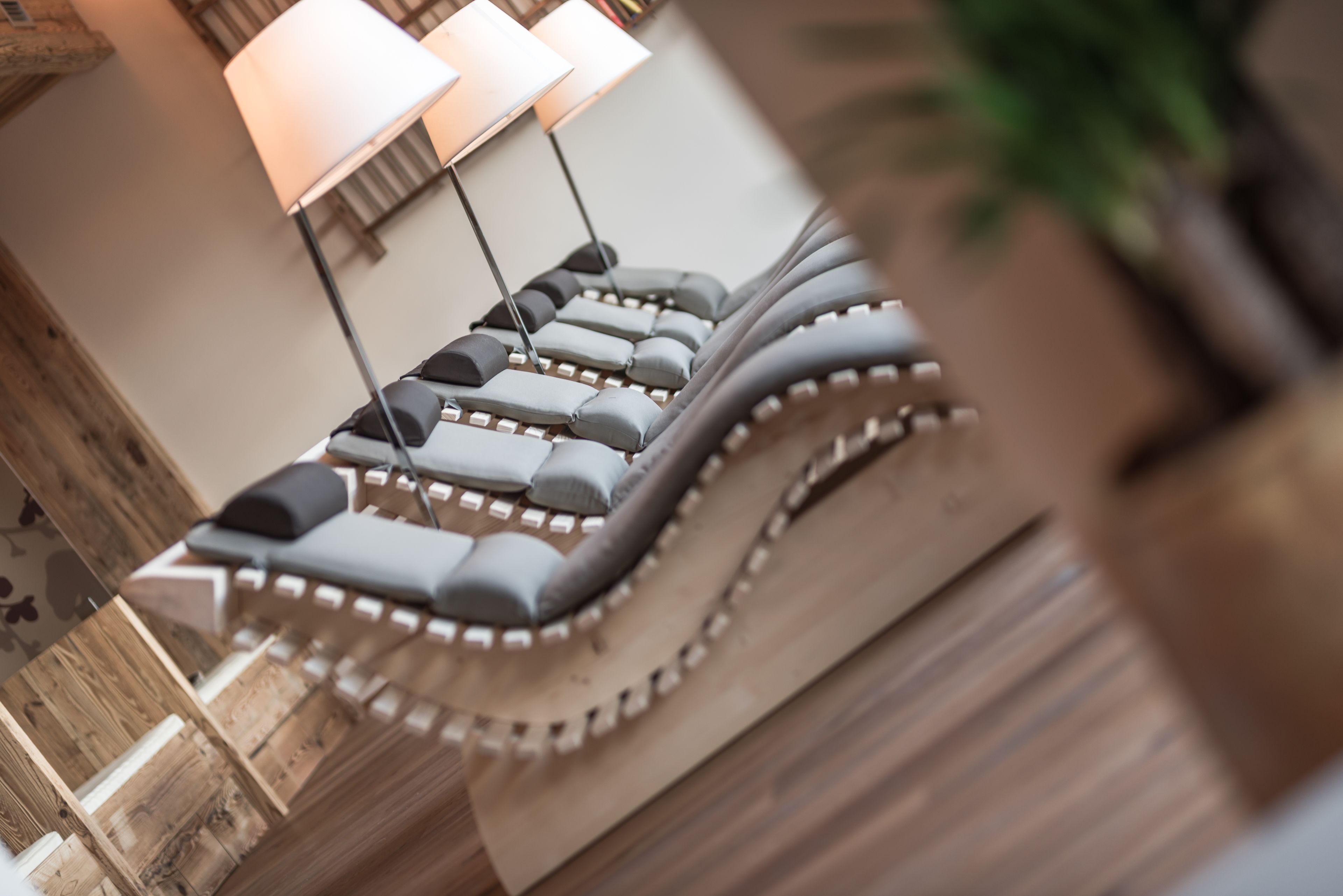 A row of massage chairs in a spa area with wooden walls and a lamp in the background.