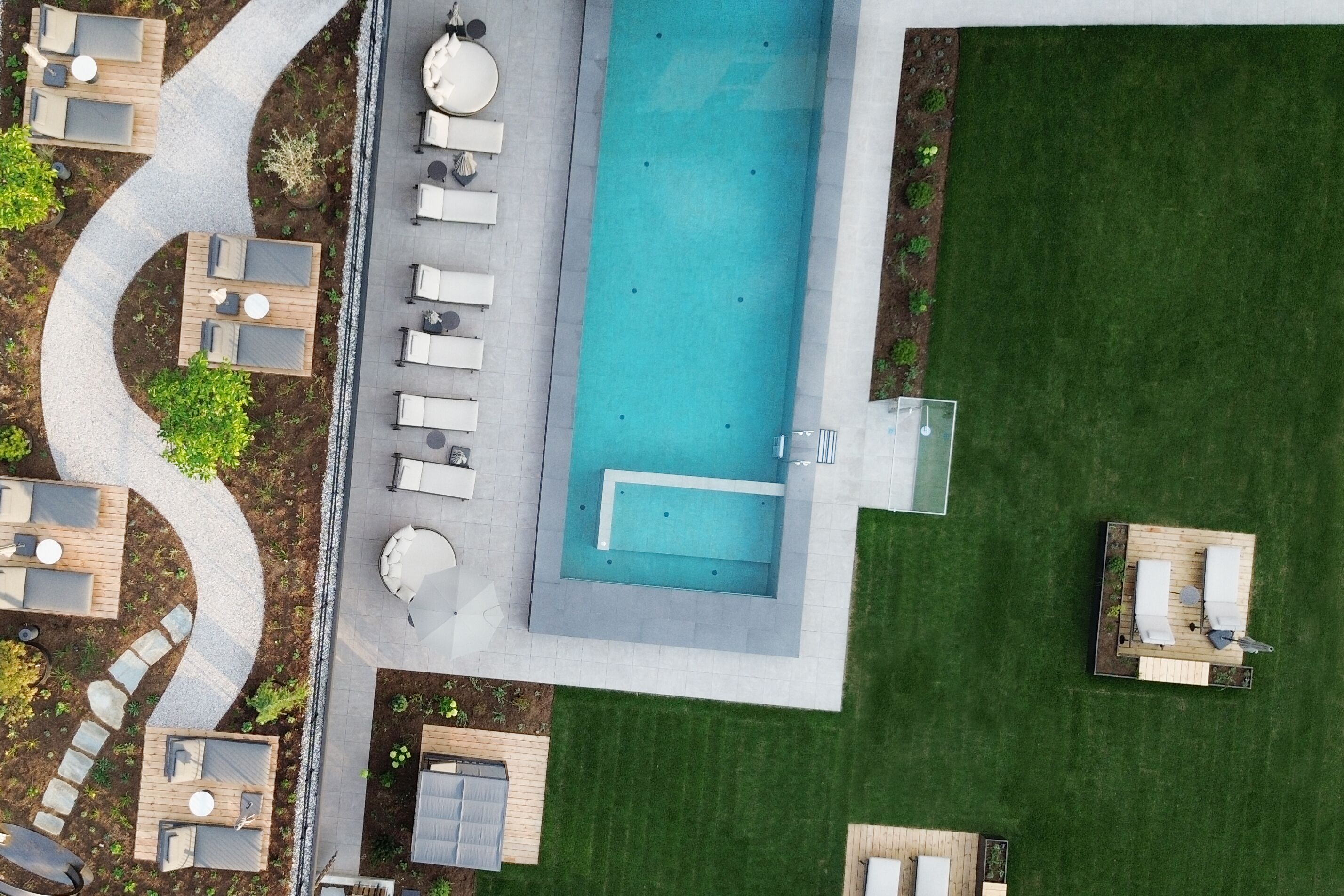 Una piscina al aire libre, sombrillas, sillones reclinables de piscina