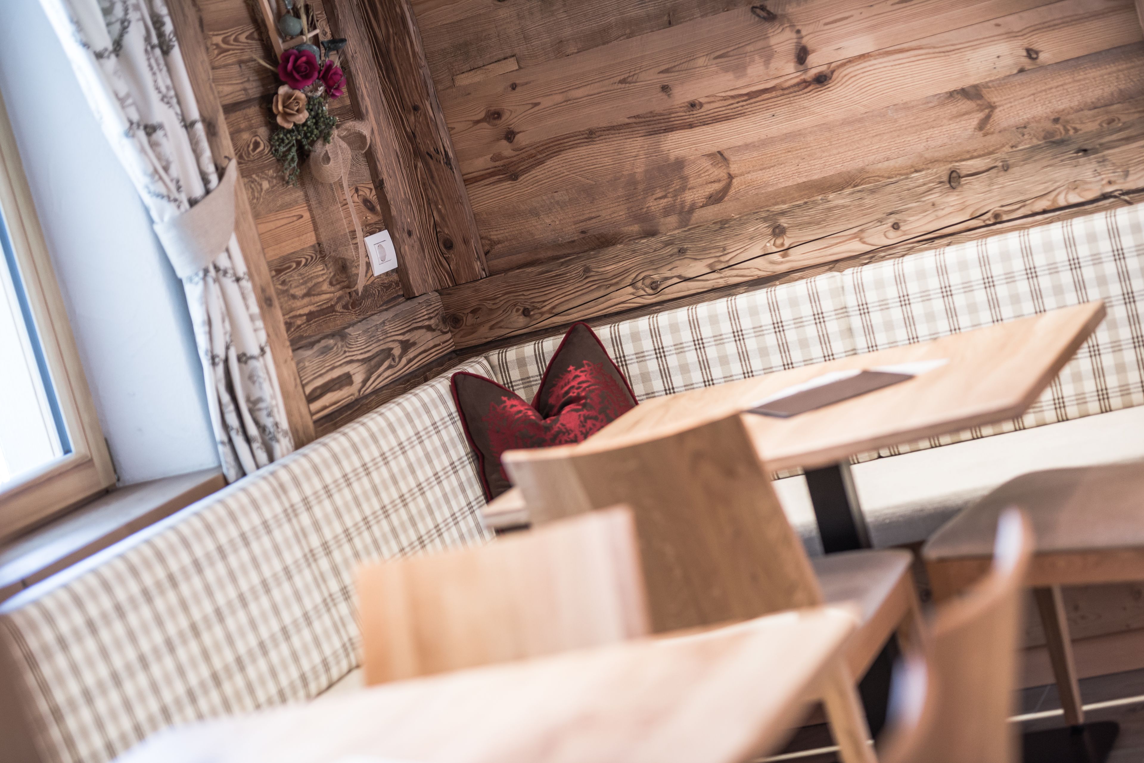 A wooden interior with a checkered bench and a table.