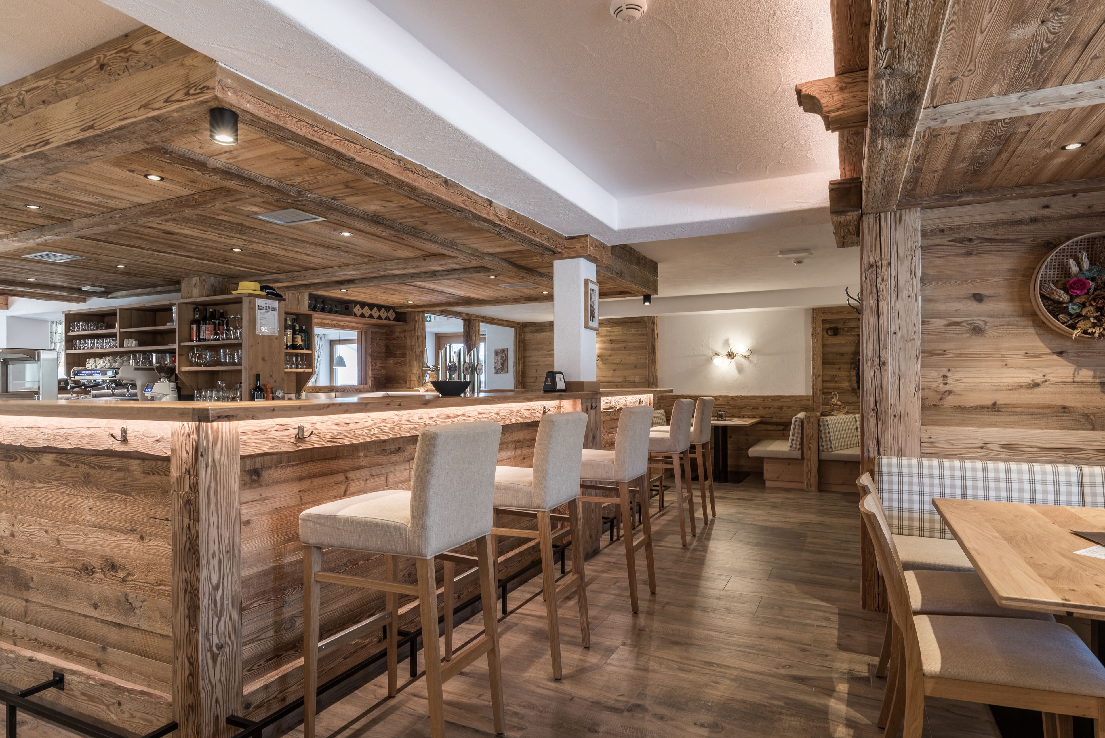 A rustic interior with a wooden bar area, seating, and a visible kitchen in the background.