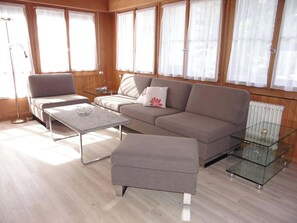 A modern living room with a sofa, a coffee table, and an ottoman.