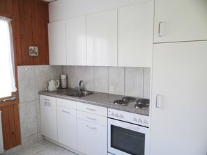 A kitchen with white cabinets, a stainless steel sink, a stove, and a small oven. - Valentine Appartement/Fewo 5-Bettwohnung by Interhome (Engelberg)
