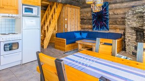 A rustic log cabin interior with a kitchen, wooden staircase, blue sofa, and a dining table. - Rinnekieppi 2 by Interhome (Kuusamo)