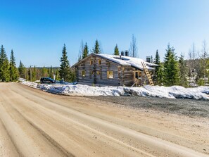 A log cabin with a dirt road in front, surrounded by snow and trees. - Rinnekieppi 2 by Interhome (Kuusamo)