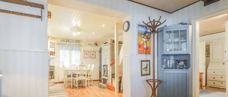 A spacious kitchen with wooden flooring, a dining area with chairs, and a blue cabinet with glass doors.