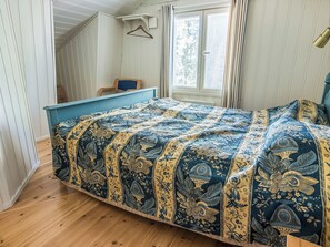 Un dormitorio con cama, piso de madera, una ventana con persianas y una silla.