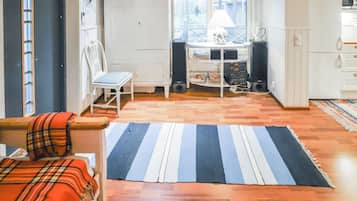 Ett mysigt vardagsrum med en randig matta, en rutig soffa och en matplats med ett bord och stolar.
