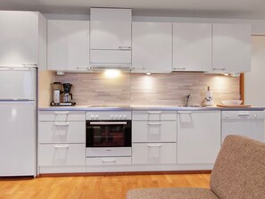A modern kitchen with white cabinets, a Bosch oven, and a coffee machine.