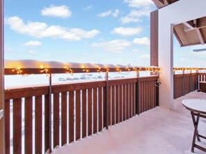 En balkon med udsigt til et sneklædt landskab og parkerede biler.