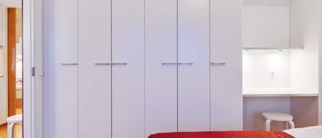 A bedroom with a bed, a wardrobe, and a desk with a chair.