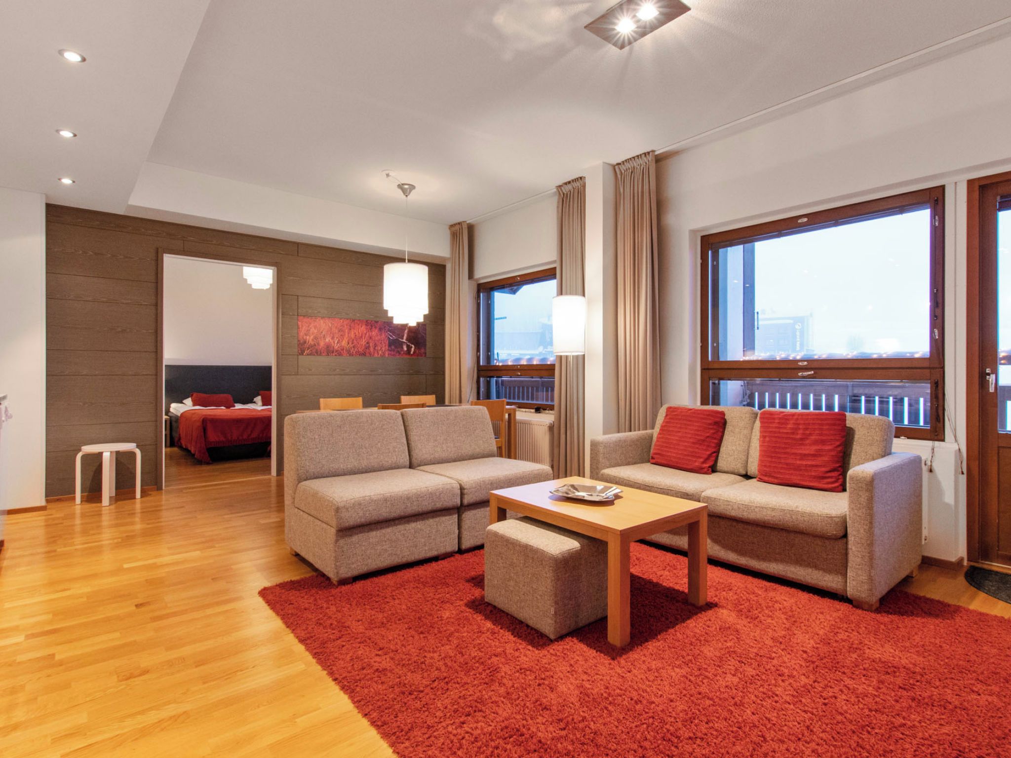 A modern living room with two sofas, a coffee table, and a red rug.