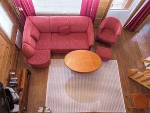 A room with a red sofa, a round wooden table, and a wooden floor.
