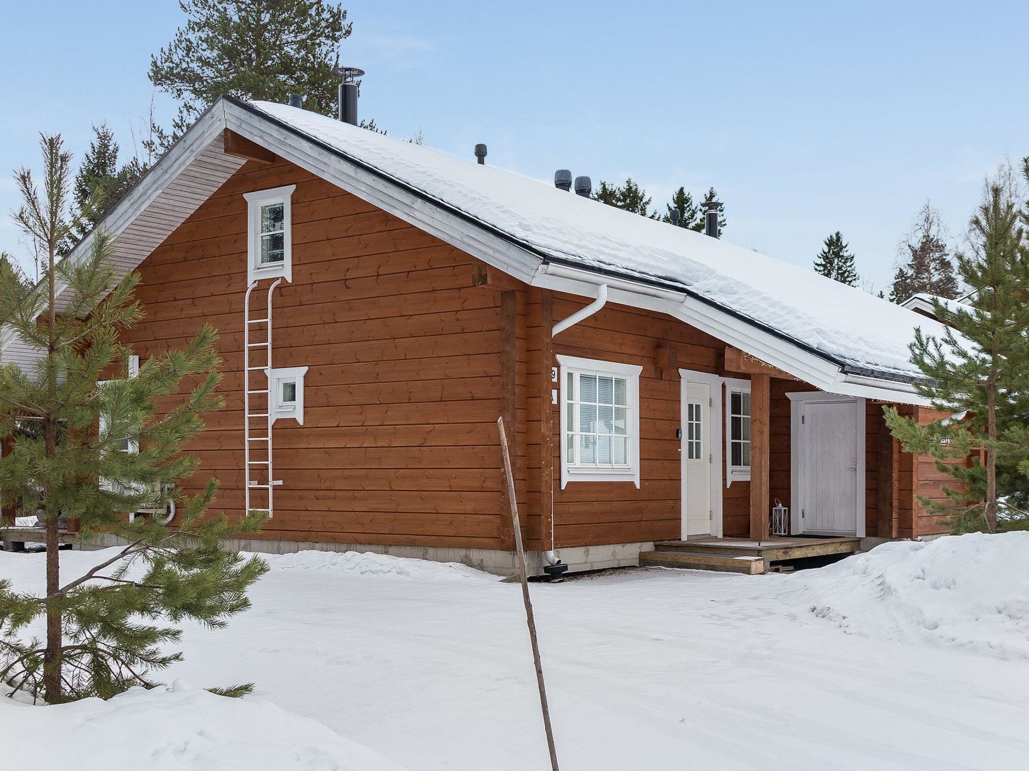 Une cabane en bois avec un toit en pente, une porte d’entrée et un petit porche.