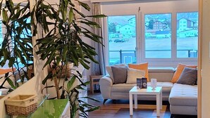 A modern living room with a sofa, coffee table, and a large potted plant. - Haus Samurai by Interhome (Saas-Grund)