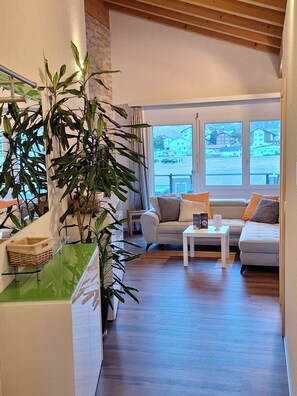 Ein modernes Wohnzimmer mit einer Couch, einem Couchtisch und einer großen Topfpflanze.