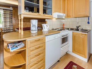 Una cocina compacta con armarios de madera, una cafetera Bosch, un hervidor, una estufa y un lavavajillas.
