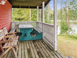 A wooden deck with a picnic table and benches, overlooking a body of water. - Mäntylä by Interhome (Nurmes)