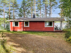 A small red cabin with a metal roof, a chimney, and a porch with a bench. - Mäntylä by Interhome (Nurmes)