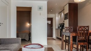 Ein modernes Wohnzimmer mit einer Couch, einem Couchtisch mit einem gewebten Korb und einem Essbereich mit Holzsesseln und einem Tisch.