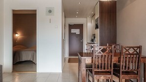 Ein modernes Hotelzimmer mit Essbereich, einem Bett und einer Küchenzeile.