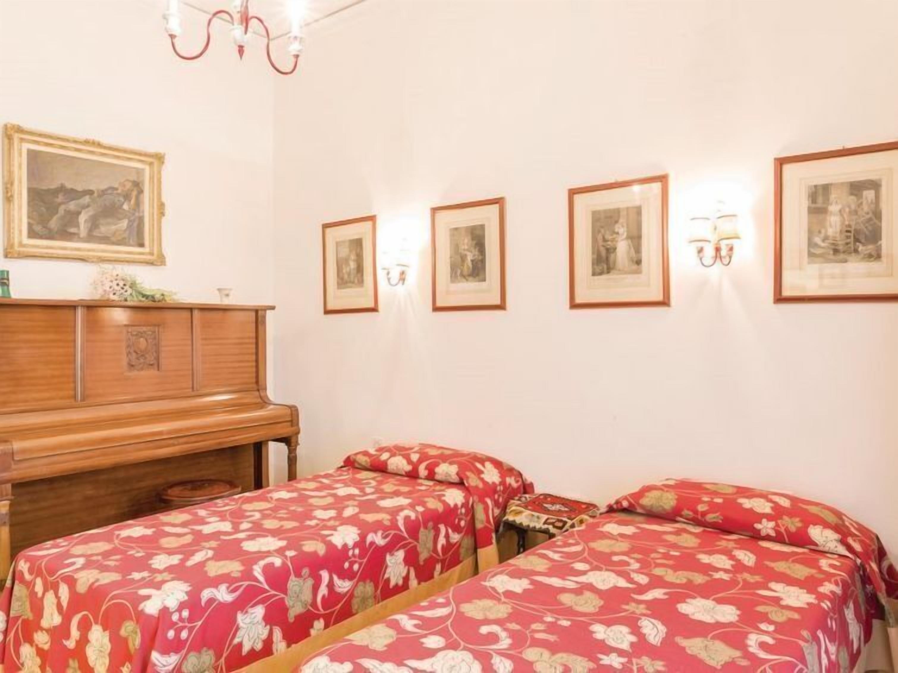 A room with two beds, a wooden dresser, and framed pictures on the wall.