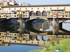 A bridge with multiple arches over a calm river, reflecting the buildings on either side. - La Torretta by Interhome (Florence)