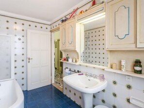 A bathroom with a white sink, a mirror, and a shower. There are decorative tiles on the walls and a patterned floor. - La Torretta by Interhome (Florence)
