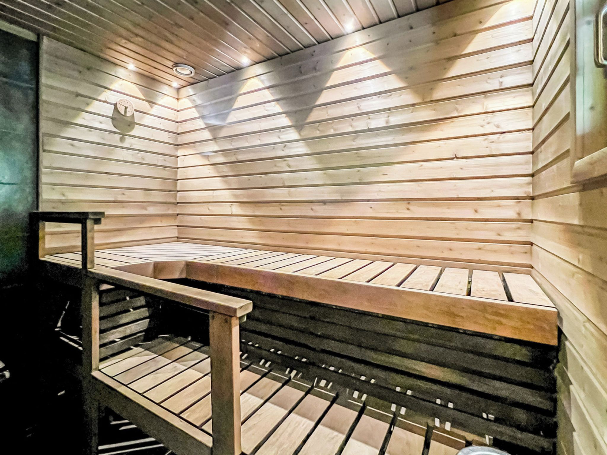 A sauna with wooden slats, a bench, and a metal frame.