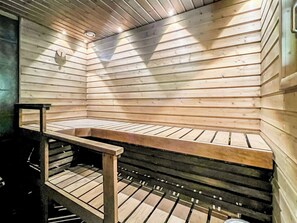 Una sauna con listones de madera, un banco y una estructura de metal.