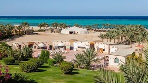 Un resort con un cortile centrale, palme e vista sul mare.