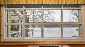 Habitació amb una finestra gran que dona a un llac i arbres.