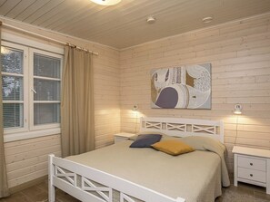 A bedroom with a bed, bedside tables, a window with curtains, and a wall-mounted artwork. - Villa siesta by Interhome (Hämeenlinna)