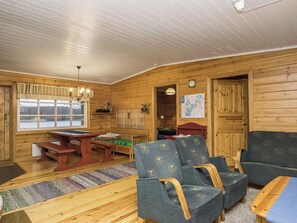 A cozy cabin interior with a wooden interior, a dining table, two chairs, a sofa, and a view through a window. - Villa siesta by Interhome (Hämeenlinna)