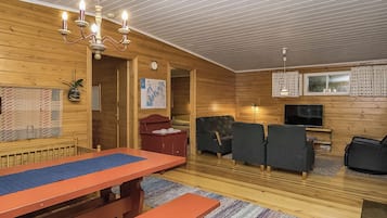 Un intérieur en bois comprenant une table de billard, un coin salon et un téléviseur.