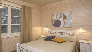 Un dormitori amb un llit, una tauleta de nit, una finestra amb cortines i una obra d'art penjada a la paret.