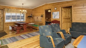 Interior acollidor d'una cabana amb parets de fusta, una taula de dinar, cadires i un sofà.