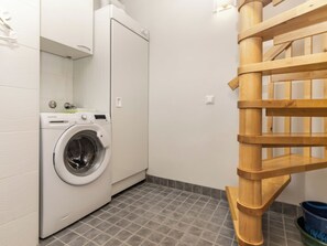 Een wasserette met een wasmachine, een droger en een houten trap.