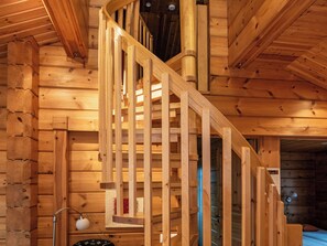 A wooden staircase with a handrail, leading to an upper level.