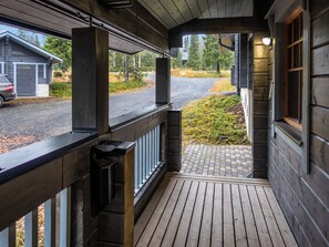 En træterrasse med udsigt til en vej og grøn bevoksning.