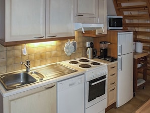 Cozinha compacta com pia, fogão, forno e micro-ondas.
